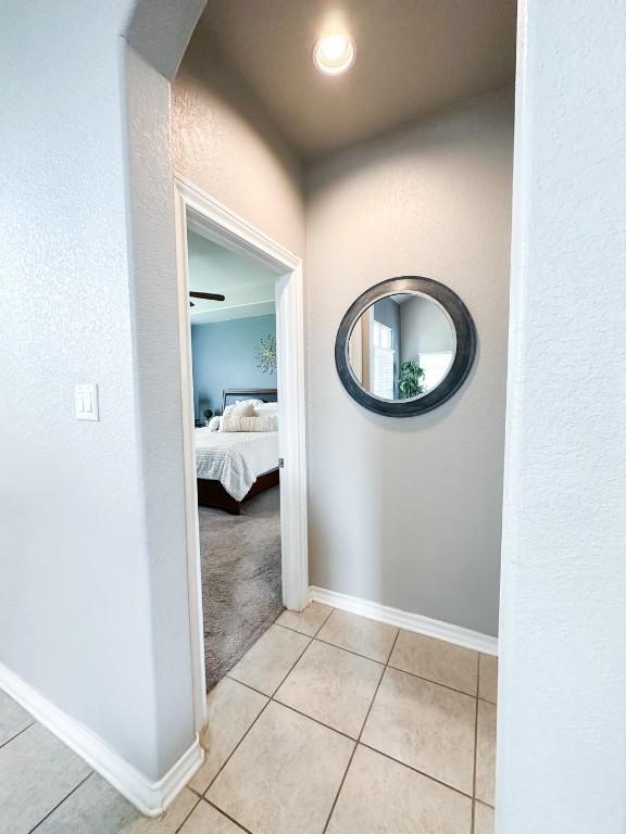 3119 Brand Iron Dr, San Marcos, TX 78666 - hall with light tile patterned flooring, arched walkways, baseboards, a textured wall, and light colored carpet