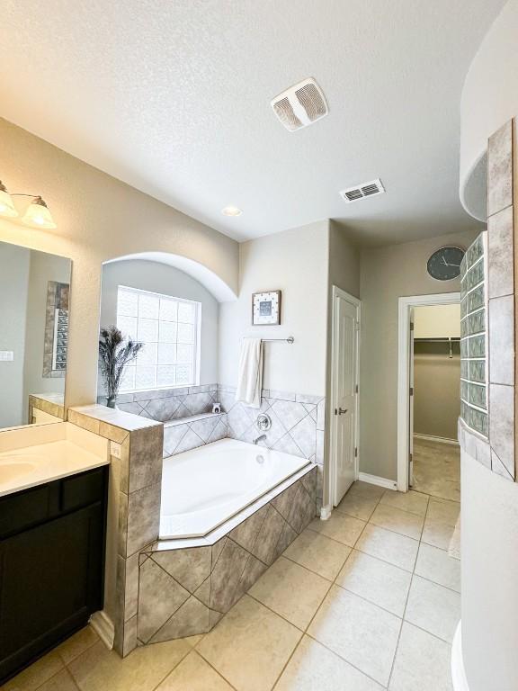 3119 Brand Iron Dr, San Marcos, TX 78666 - full bathroom with vanity, a bath, tile patterned floors, a spacious closet, and a textured ceiling