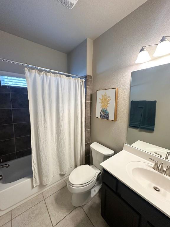 3119 Brand Iron Dr, San Marcos, TX 78666 - bathroom with vanity, toilet, tile patterned floors, shower / bath combo with shower curtain, and a textured wall