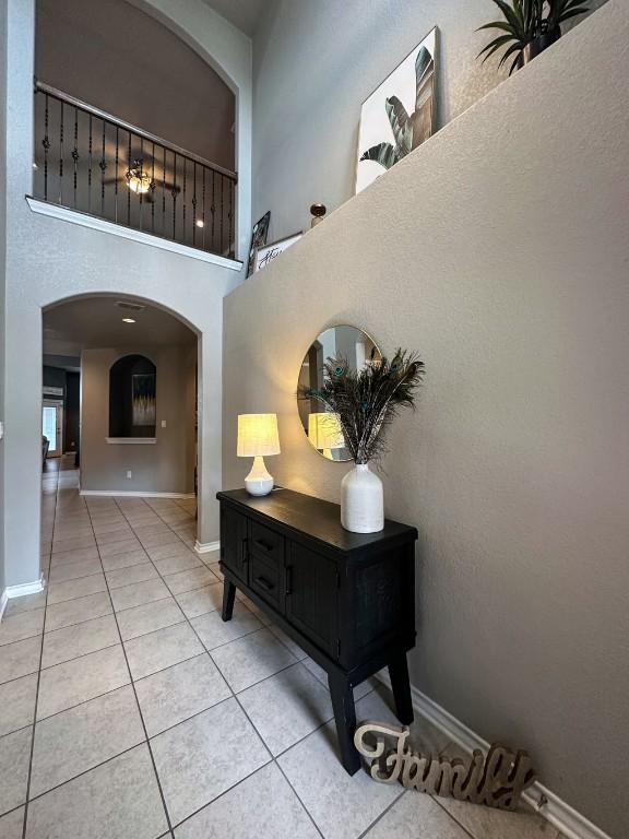 3119 Brand Iron Dr, San Marcos, TX 78666 - hall with light tile patterned flooring, arched walkways, baseboards, and a towering ceiling