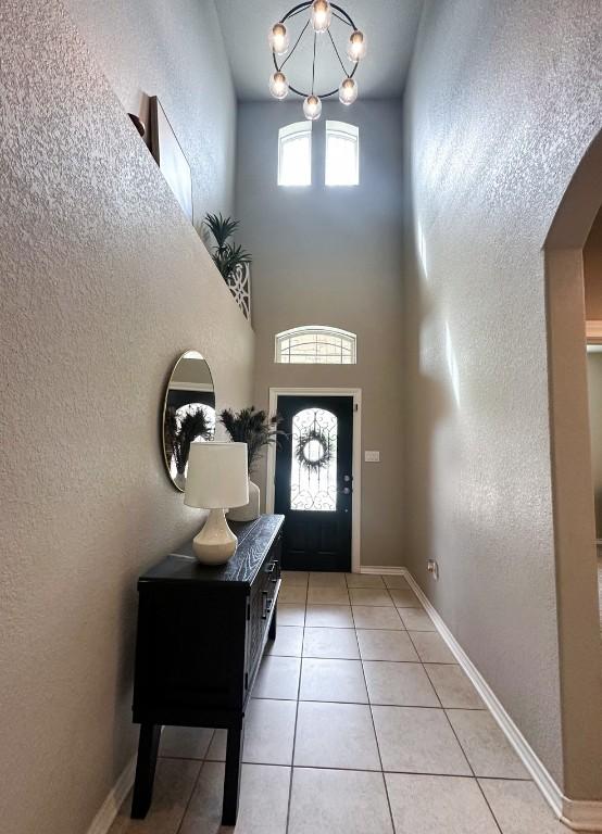 3119 Brand Iron Dr, San Marcos, TX 78666 - foyer entrance featuring arched walkways, light tile patterned flooring, a chandelier, a towering ceiling, and baseboards