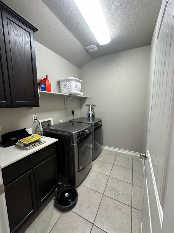 3119 Brand Iron Dr, San Marcos, TX 78666 - washroom featuring washer and clothes dryer, a textured ceiling, light tile patterned flooring, cabinet space, and baseboards