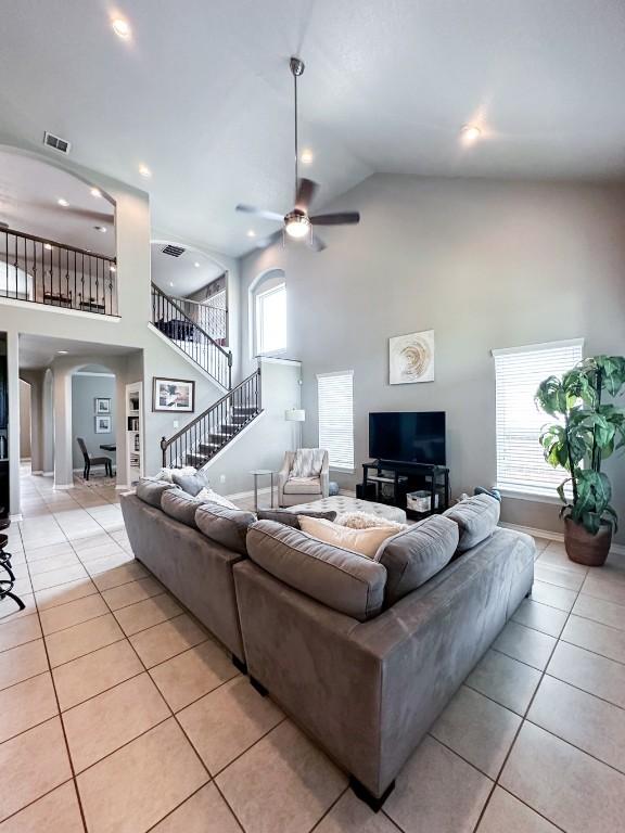 3119 Brand Iron Dr, San Marcos, TX 78666 - living room with high vaulted ceiling, arched walkways, light tile patterned floors, ceiling fan, and stairway