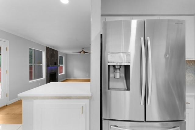 6200 La Naranja Ln, Austin, TX 78749 - kitchen featuring stainless steel refrigerator with ice dispenser, white cabinetry, ceiling fan, light countertops, and light wood finished floors