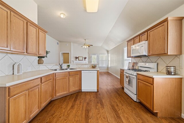 117 Village Commons Blvd, Georgetown, TX 78633 - kitchen with white appliances, a sink, lofted ceiling, a peninsula, and wood finished floors