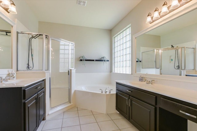 bathroom featuring a stall shower, a garden tub, tile patterned floors, and two vanities