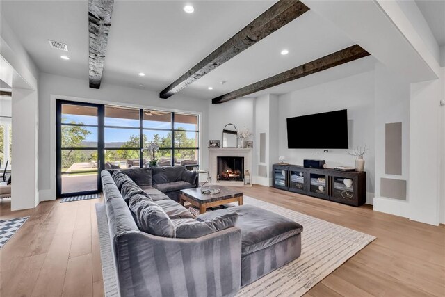 11705 Shoreview Overlook, Austin, TX 78732 - living room with healthy amount of natural light, beamed ceiling, a warm lit fireplace, light wood-style floors, and recessed lighting