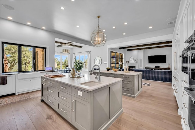 11705 Shoreview Overlook, Austin, TX 78732 - kitchen with a kitchen island with sink, gray cabinets, open floor plan, recessed lighting, and light wood-style floors