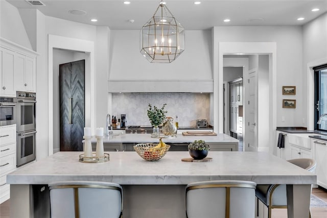 11705 Shoreview Overlook, Austin, TX 78732 - kitchen with an island with sink, stainless steel double oven, recessed lighting, a sink, and tasteful backsplash