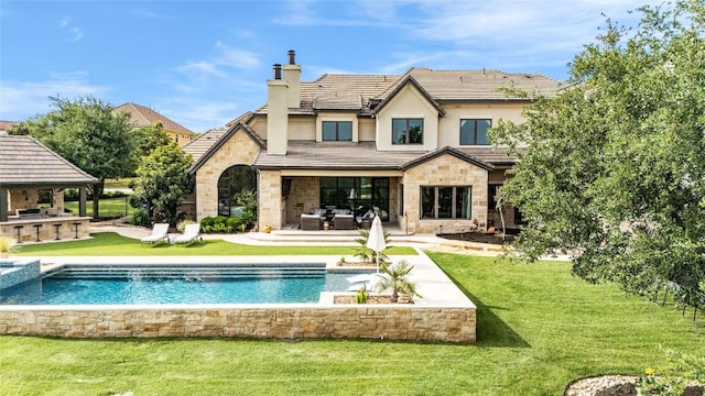 11705 Shoreview Overlook, Austin, TX 78732 - rear view of property featuring an outdoor kitchen, a chimney, stone siding, and a lawn