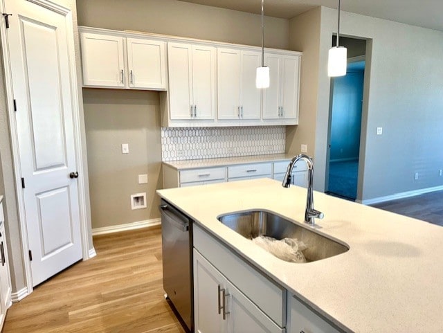 328 Milkwood Ter, Dripping Springs, TX 78620 - kitchen featuring stainless steel dishwasher, a sink, light wood-style floors, decorative light fixtures, and white cabinets