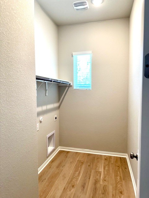 328 Milkwood Ter, Dripping Springs, TX 78620 - laundry area with hookup for an electric dryer, light wood-type flooring, and baseboards