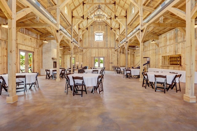 dining area featuring high vaulted ceiling, plenty of natural light, a chandelier, and finished concrete flooring