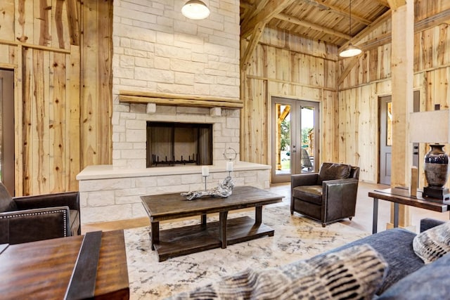 living area with wooden ceiling, high vaulted ceiling, a fireplace, wood walls, and beam ceiling