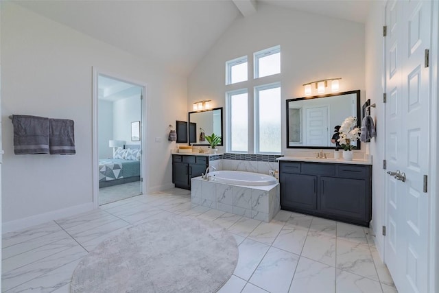 full bath featuring marble finish flooring, a bath, baseboards, two vanities, and high vaulted ceiling
