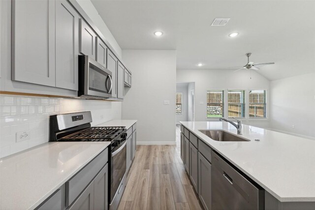 200 Hidalgo Ln, Elgin, TX 78621 - kitchen with appliances with stainless steel finishes, a sink, light wood finished floors, gray cabinetry, and a ceiling fan