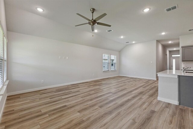 200 Hidalgo Ln, Elgin, TX 78621 - unfurnished living room featuring a ceiling fan, a sink, light wood finished floors, baseboards, and lofted ceiling