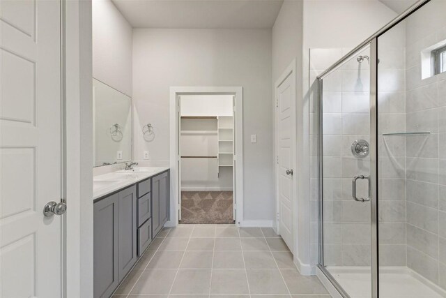 200 Hidalgo Ln, Elgin, TX 78621 - full bathroom featuring tile patterned flooring, a stall shower, double vanity, a spacious closet, and baseboards