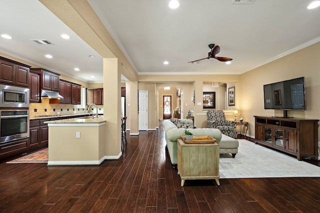 1720 Foxboro Ln, Cedar Park, TX 78613 - living room featuring crown molding, arched walkways, dark wood-style floors, ceiling fan, and recessed lighting