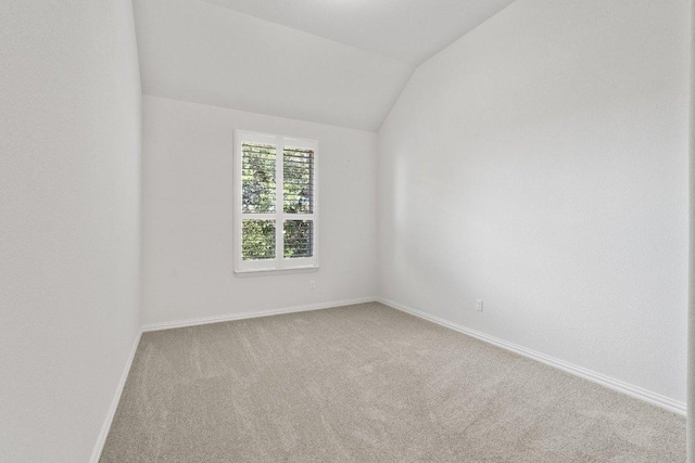 carpeted empty room with baseboards and lofted ceiling