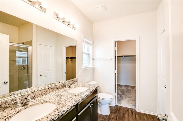 253 Beechnut Dr, Buda, TX 78610 - bathroom featuring toilet, a shower stall, wood finished floors, double vanity, and a walk in closet