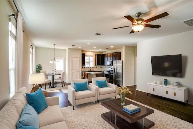 253 Beechnut Dr, Buda, TX 78610 - living room featuring dark wood-style floors, a ceiling fan, recessed lighting, baseboards, and a chandelier