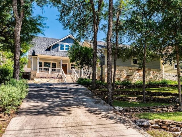 view of front of house featuring a porch, driveway, stone siding, and board and batten siding