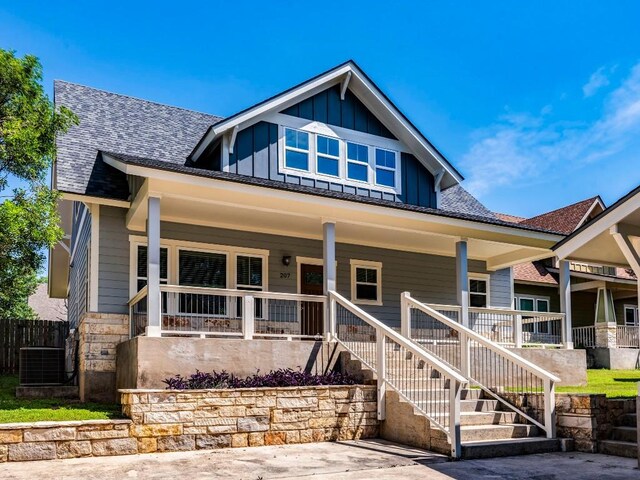 view of front of house with covered porch, board and batten siding, central AC unit, and roof with shingles
