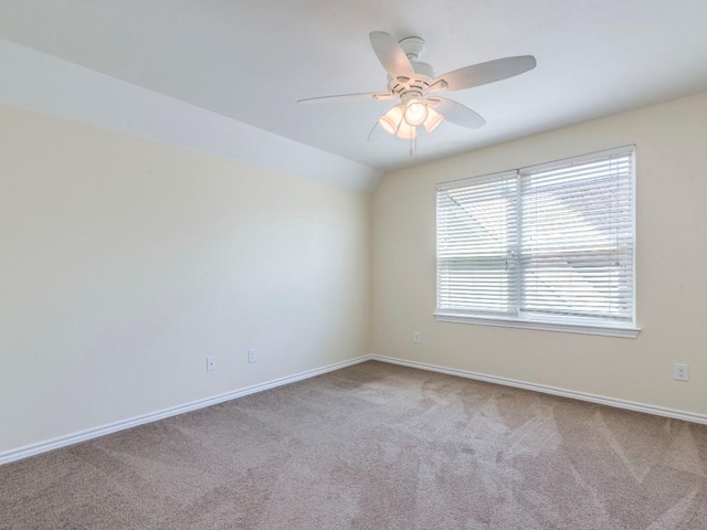 carpeted spare room with ceiling fan, baseboards, and vaulted ceiling