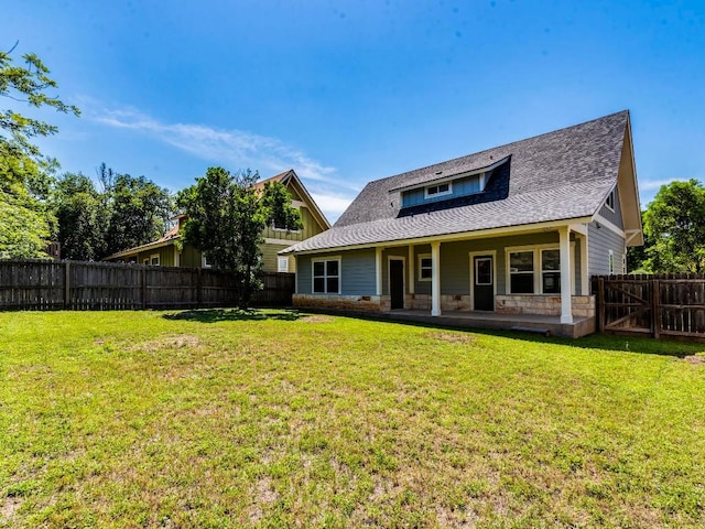 rear view of property featuring stone siding, a patio, and a shingled roof