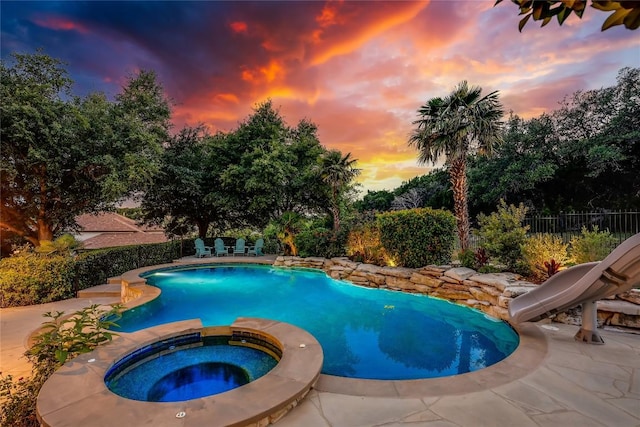 2116 Demona Dr, Austin, TX 78733 - pool at dusk featuring a water slide, a patio, and a pool with connected hot tub