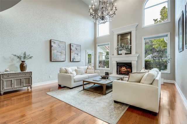 2116 Demona Dr, Austin, TX 78733 - living area featuring a warm lit fireplace, wood finished floors, a chandelier, and a towering ceiling