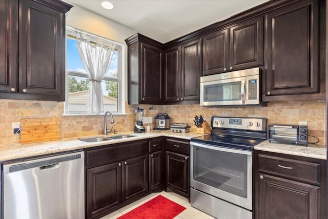 113 N Buckhorn Dr, Bastrop, TX 78602 - kitchen with stainless steel appliances, a sink, backsplash, dark brown cabinetry, and light stone counters