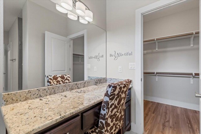 113 N Buckhorn Dr, Bastrop, TX 78602 - bathroom featuring wood finished floors, vanity, baseboards, and a spacious closet
