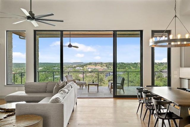 living room with light wood finished floors, healthy amount of natural light, a chandelier, and ceiling fan
