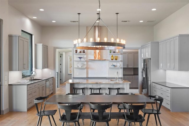 kitchen with appliances with stainless steel finishes, open shelves, light wood-style flooring, gray cabinetry, and pendant lighting