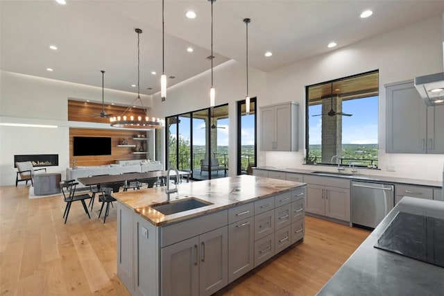 kitchen featuring gray cabinets, a sink, stainless steel dishwasher, and recessed lighting