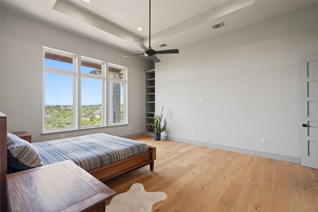 bedroom with baseboards, wood finished floors, recessed lighting, ceiling fan, and a tray ceiling