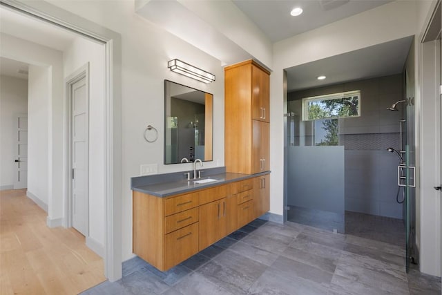 bathroom featuring walk in shower, vanity, baseboards, and recessed lighting