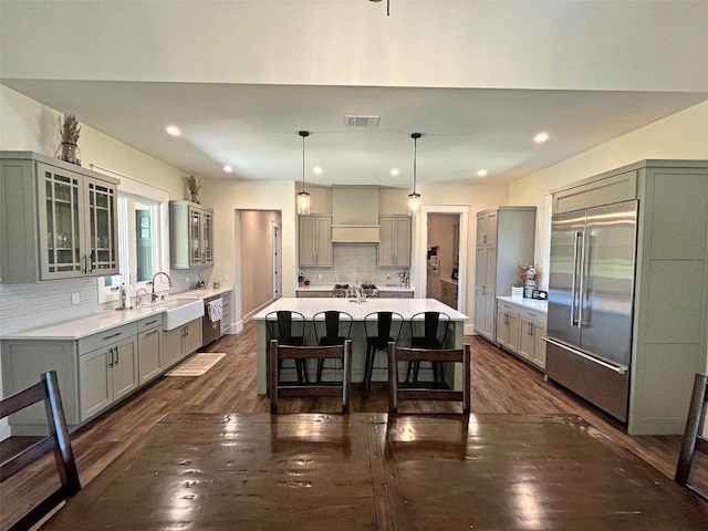 1402 Countryside Bnd, Fredericksburg, TX 78624 - kitchen with gray cabinetry, a sink, a kitchen bar, tasteful backsplash, and dark wood-type flooring