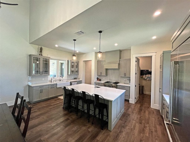 1402 Countryside Bnd, Fredericksburg, TX 78624 - kitchen with gray cabinetry, dark wood-type flooring, a sink, a kitchen island with sink, and a breakfast bar area