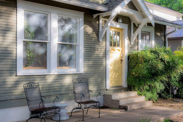 view of exterior entry with roof with shingles