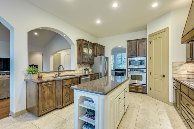 13708 Montview Dr, Austin, TX 78732 - kitchen featuring appliances with stainless steel finishes, a sink, a center island, tasteful backsplash, and dark stone countertops