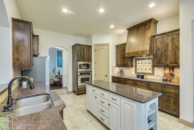 13708 Montview Dr, Austin, TX 78732 - kitchen featuring appliances with stainless steel finishes, a sink, arched walkways, custom exhaust hood, and white cabinetry