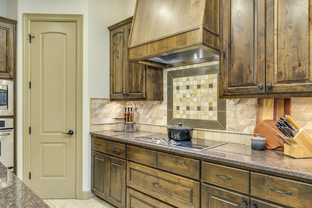 13708 Montview Dr, Austin, TX 78732 - kitchen with custom exhaust hood, backsplash, dark brown cabinetry, and dark stone countertops