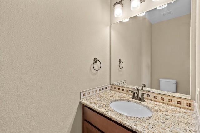 1044 Highknoll Ln, Georgetown, TX 78628 - half bathroom featuring backsplash, vanity, toilet, and a textured wall