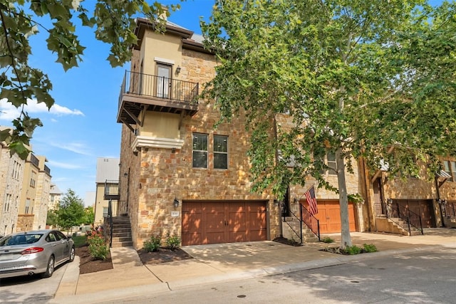1044 Highknoll Ln, Georgetown, TX 78628 - view of front facade featuring stairway, stone siding, a garage, concrete driveway, and a balcony
