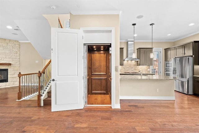 1044 Highknoll Ln, Georgetown, TX 78628 - kitchen with stainless steel appliances, wall chimney exhaust hood, crown molding, wood finished floors, and light stone counters