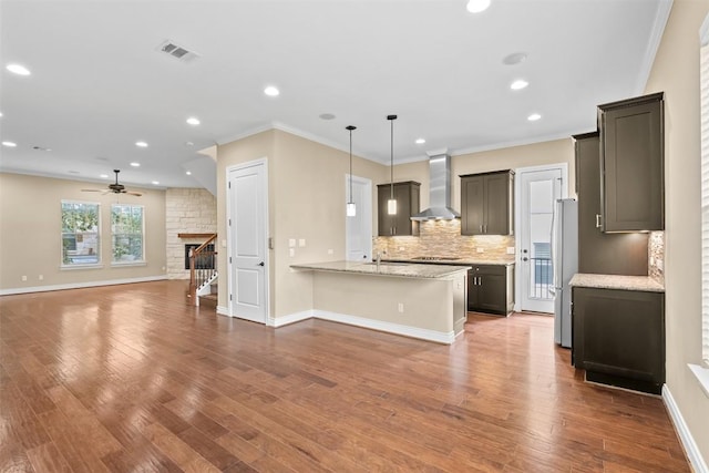 1044 Highknoll Ln, Georgetown, TX 78628 - kitchen with wall chimney range hood, open floor plan, tasteful backsplash, freestanding refrigerator, and a peninsula
