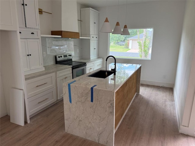 kitchen with stainless steel range with electric stovetop, wall chimney range hood, a sink, and light wood-style floors